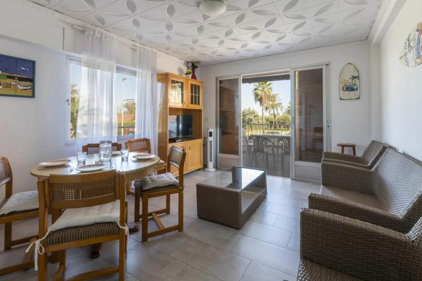A living and dining area with wicker seating and glass doors opening onto a balcony.