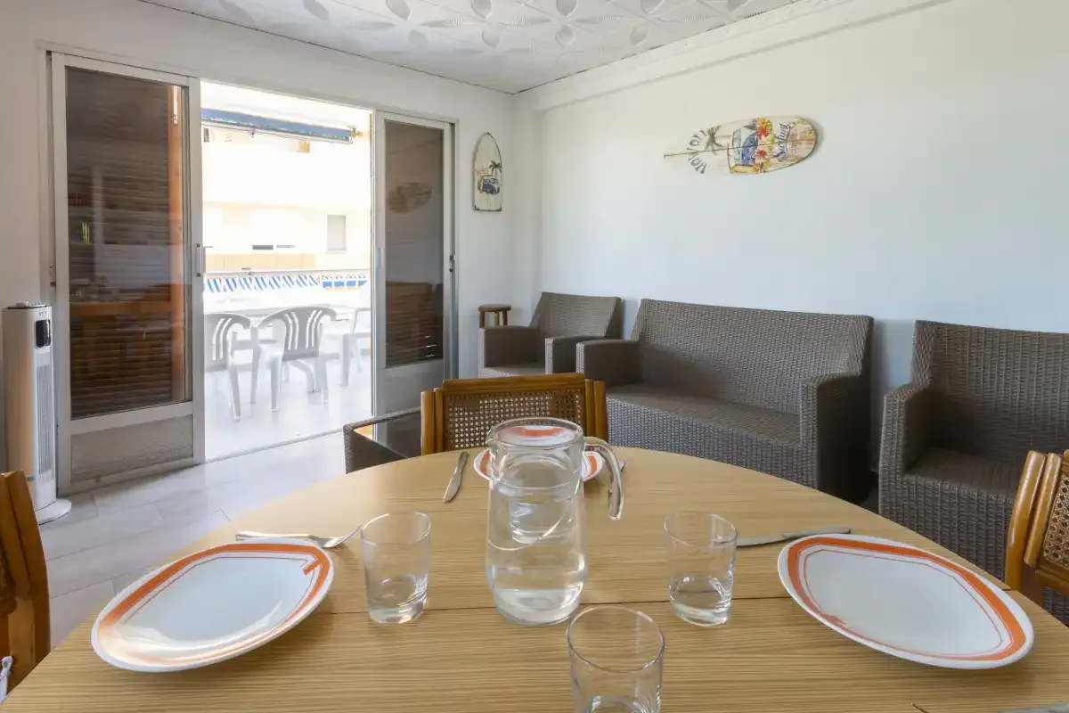 A dining area with a set table and seating beside sliding glass doors.