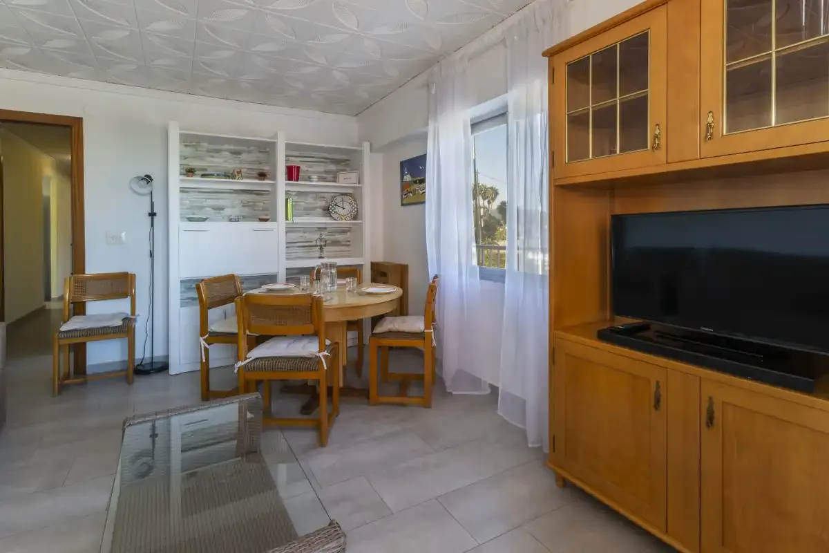 A dining and living area with a round table, chairs, and a television cabinet.