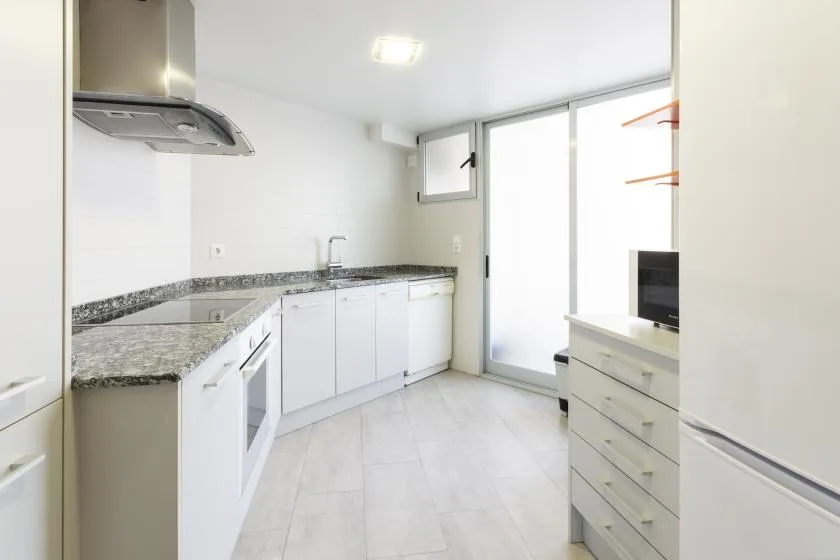 A bright kitchen with white cabinets, a countertop, and a sink.