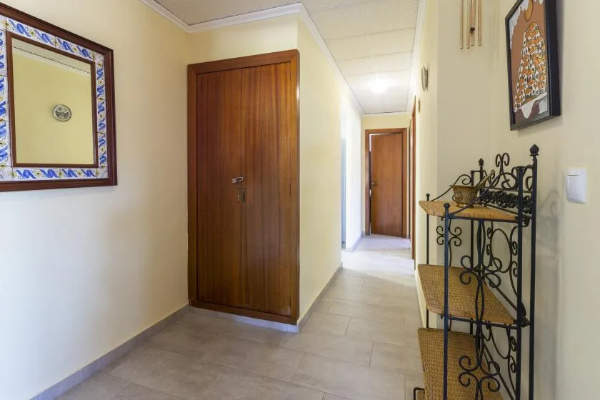 A bright hallway with wooden doors, tiled flooring, and a decorative metal console.