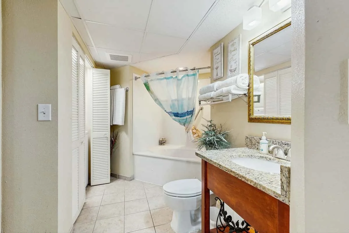 A bathroom with a bathtub, shower curtain, and vanity.