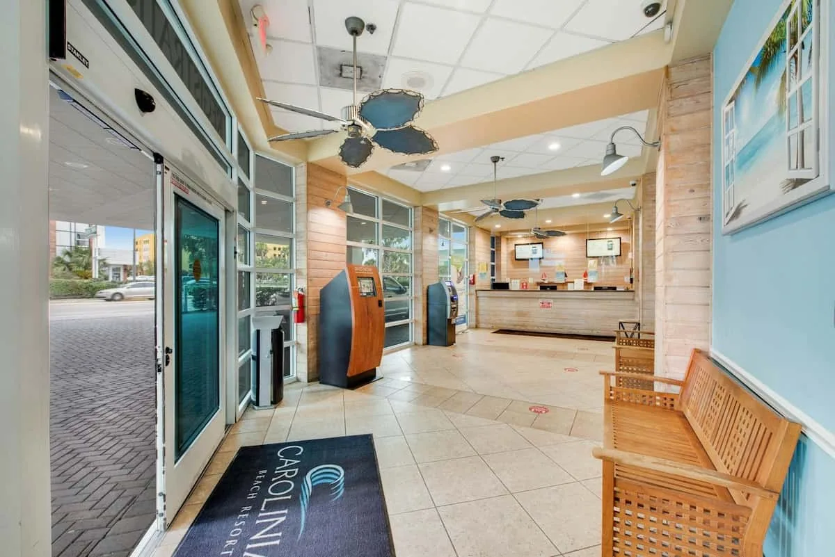 A lobby with a reception counter, seating, and large windows.