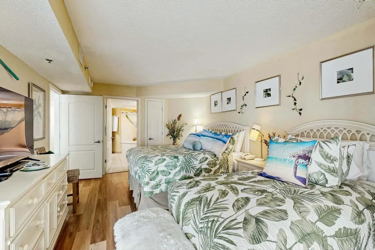 A bedroom with two beds dressed in leafy patterned bedding.