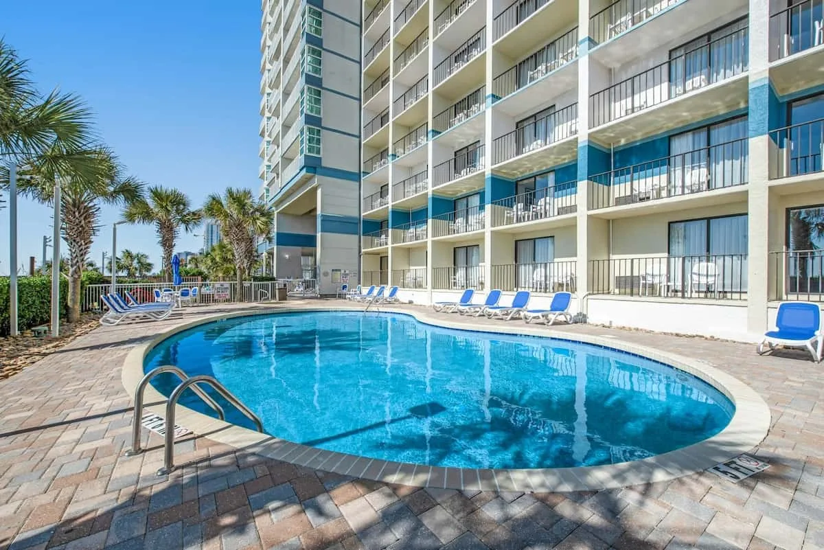 A swimming pool sits beside a high-rise building with balconies.