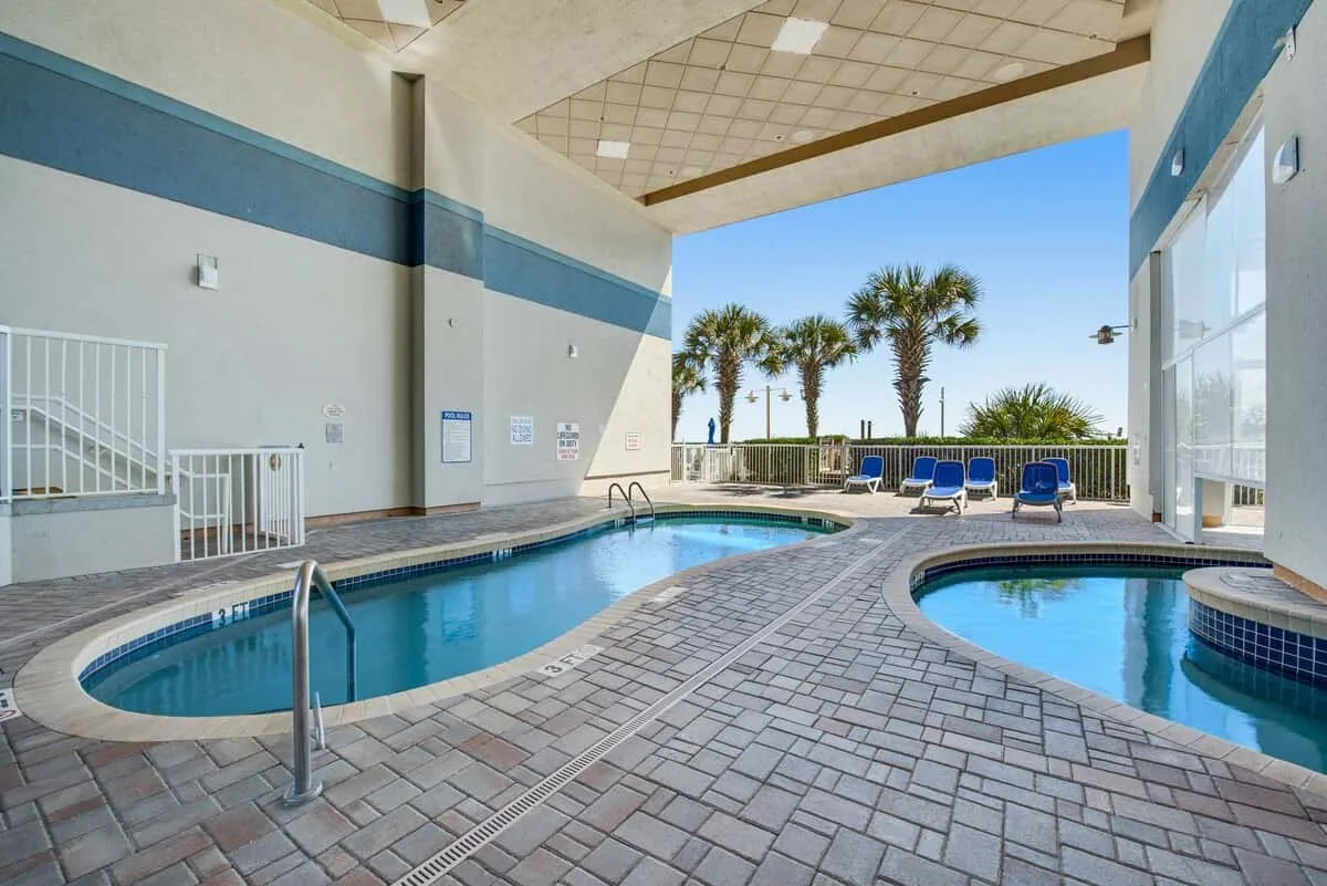 An indoor pool area opens onto an outdoor deck with lounge seating.