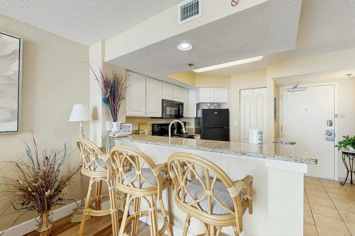 A bright kitchen and dining area with a long counter and woven seating.