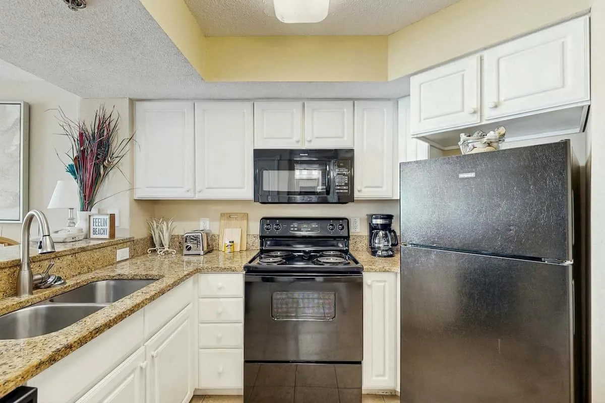 A kitchen with white cabinets, a refrigerator, and a stove.