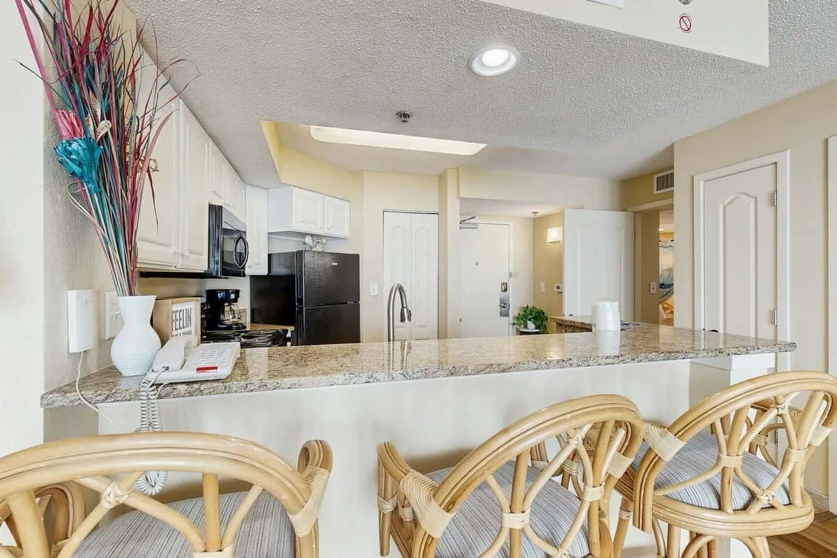 A kitchen with a breakfast bar and several woven chairs.