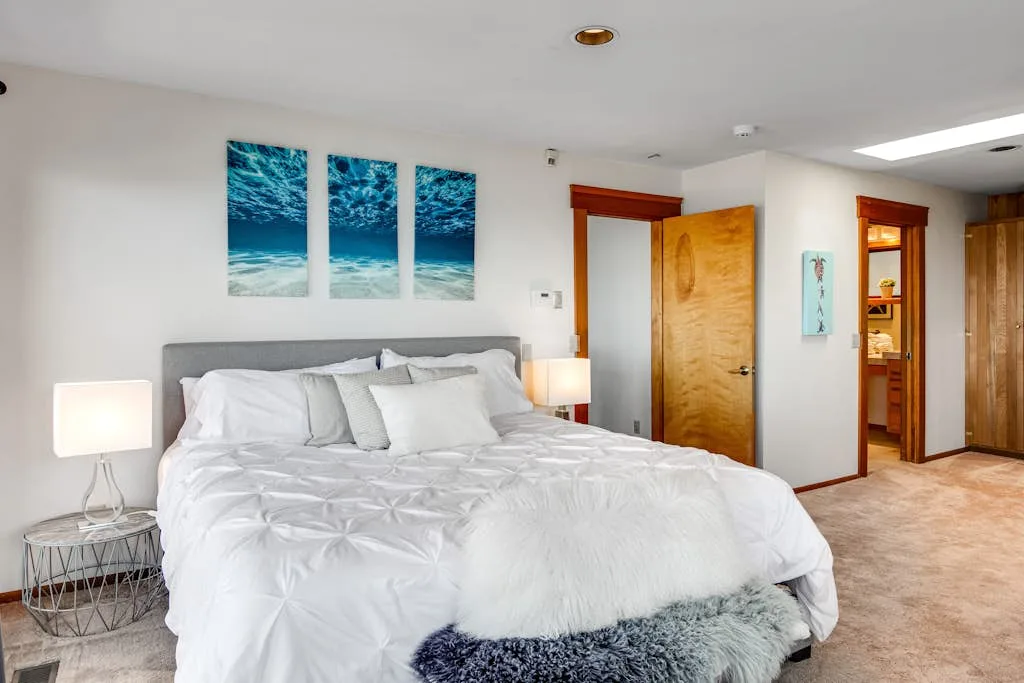 A bright bedroom with a large bed and three ocean-themed wall prints.