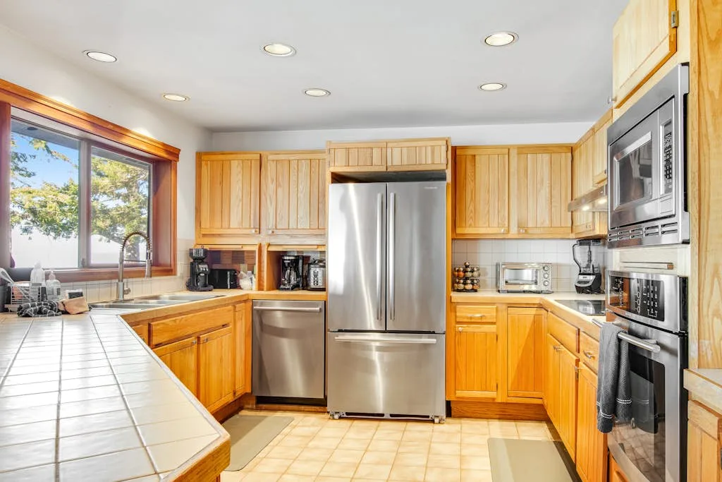 A bright kitchen with wooden cabinets and stainless-steel appliances.