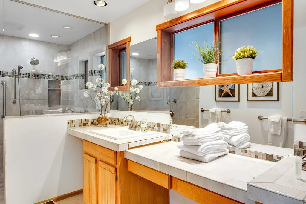 A bright bathroom with a long vanity, mirrors, and a glass shower.