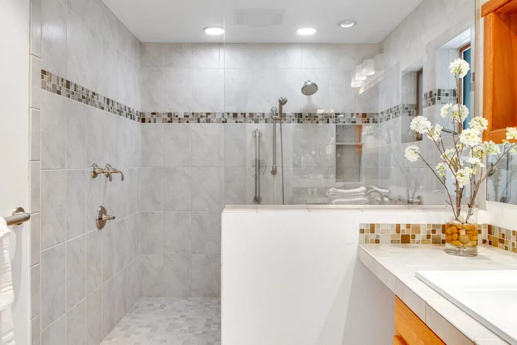 A tiled bathroom with a bathtub, shower fixtures, and a vanity.