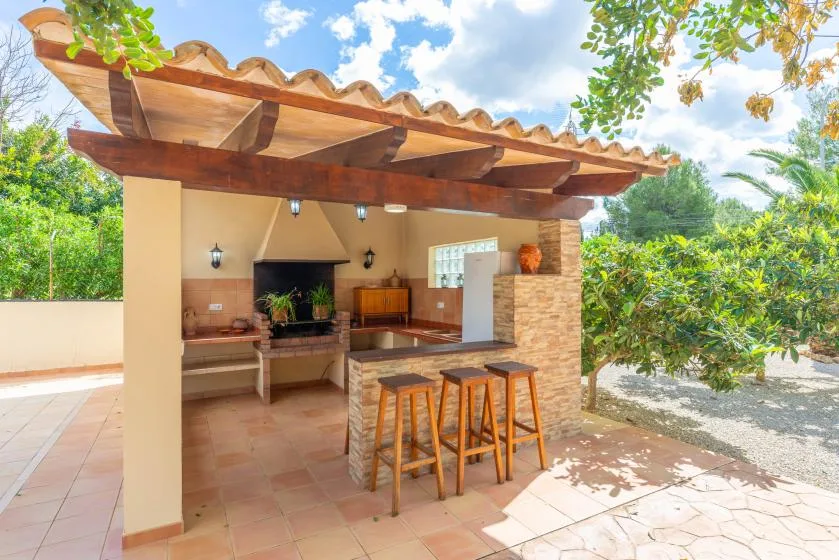 An outdoor kitchen and bar counter sit beneath a timber-covered patio.