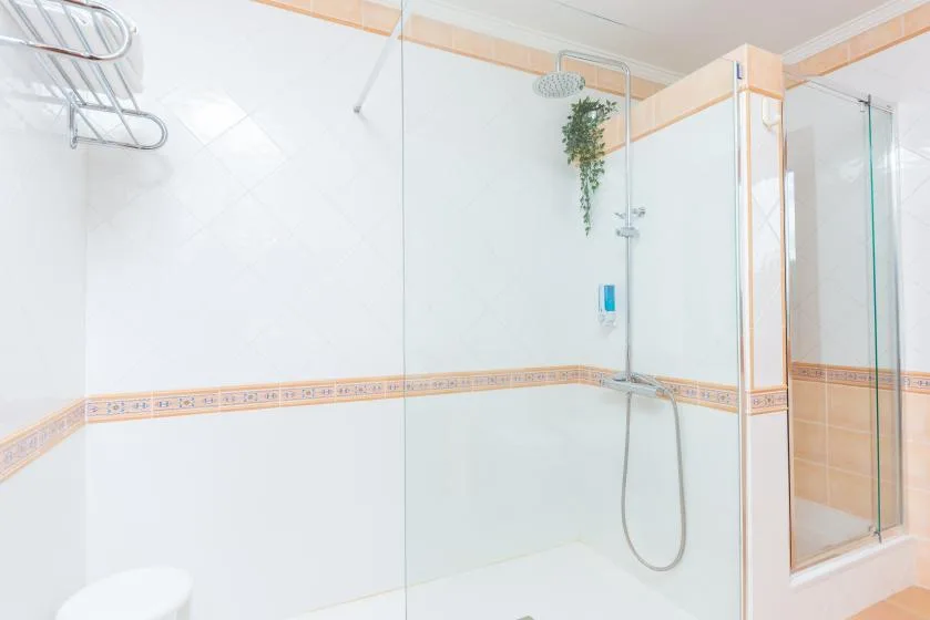 A tiled bathroom with a glass shower and wall-mounted showerhead.