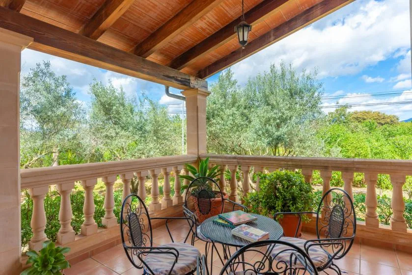 A covered terrace with outdoor seating overlooks leafy trees.