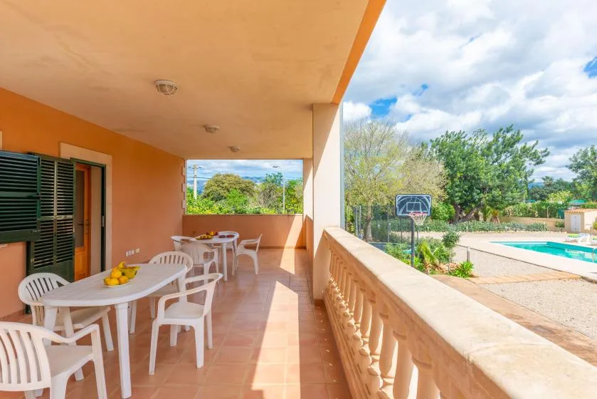 A covered outdoor dining area overlooks a swimming pool and garden.