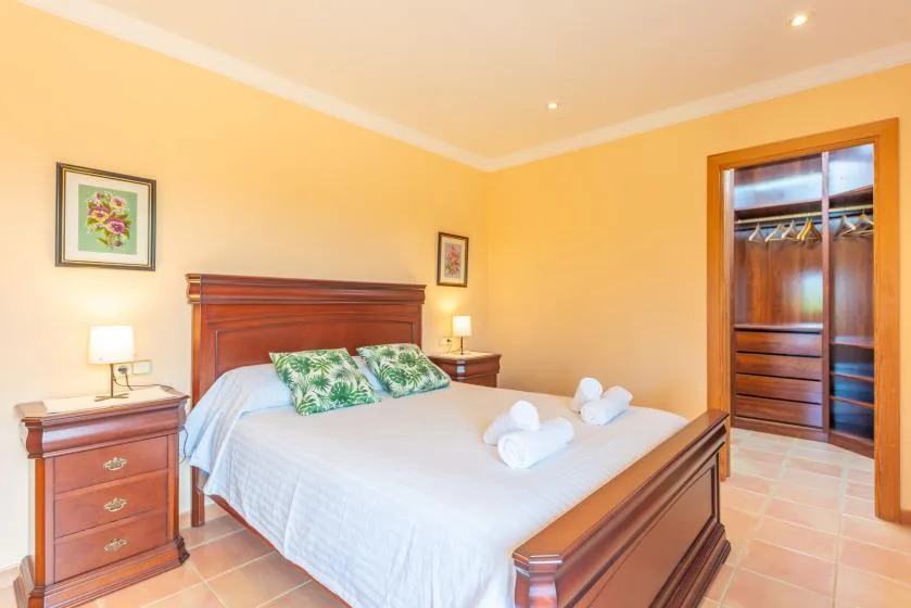 A bedroom with a neatly made bed and wooden bedside tables.