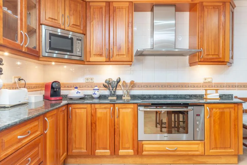A kitchen with wooden cabinets, a microwave, and a built-in oven.