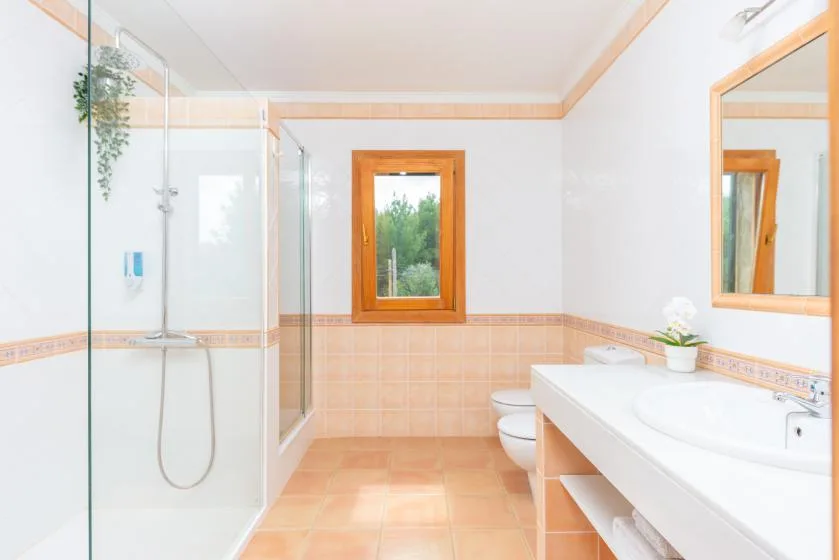 A bright bathroom with a glass shower and a long sink counter.