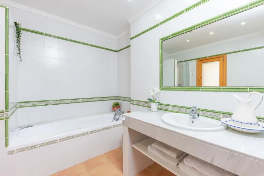 A bright bathroom has a bathtub, sink, and large wall mirror.