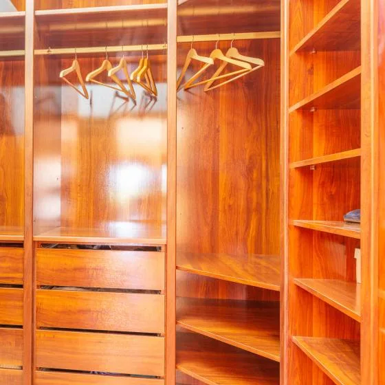 A wooden wardrobe with hanging space, drawers, and open shelving.
