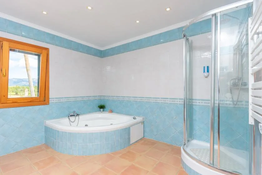 A tiled bathroom with a corner bathtub and a glass shower.