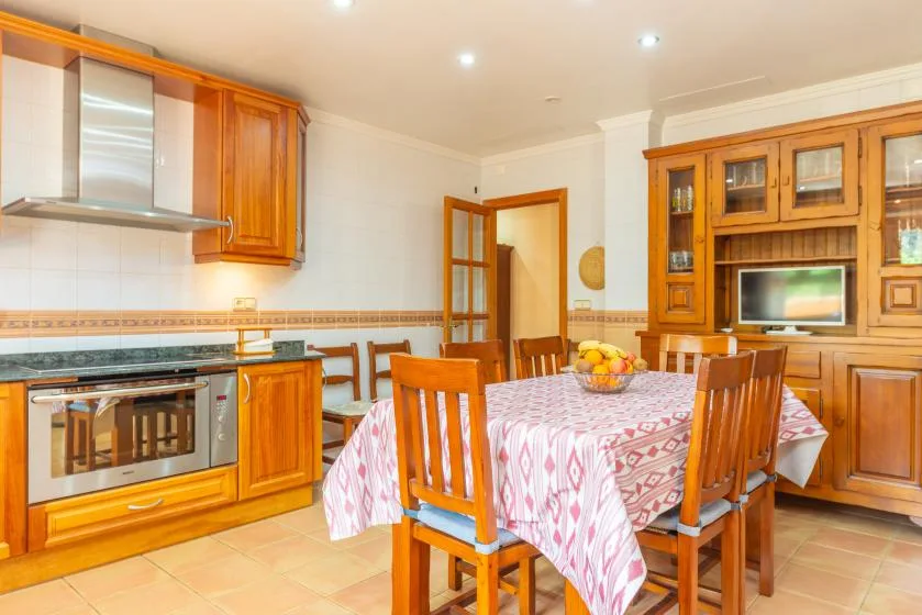 A dining area with a wooden table and chairs beside built-in kitchen cabinetry.