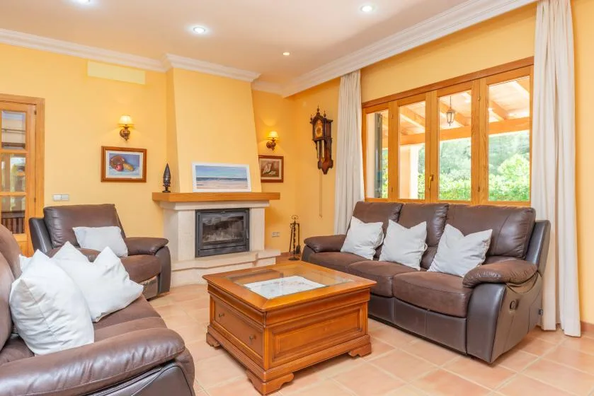 A living room with brown seating, a wooden coffee table, and a fireplace.