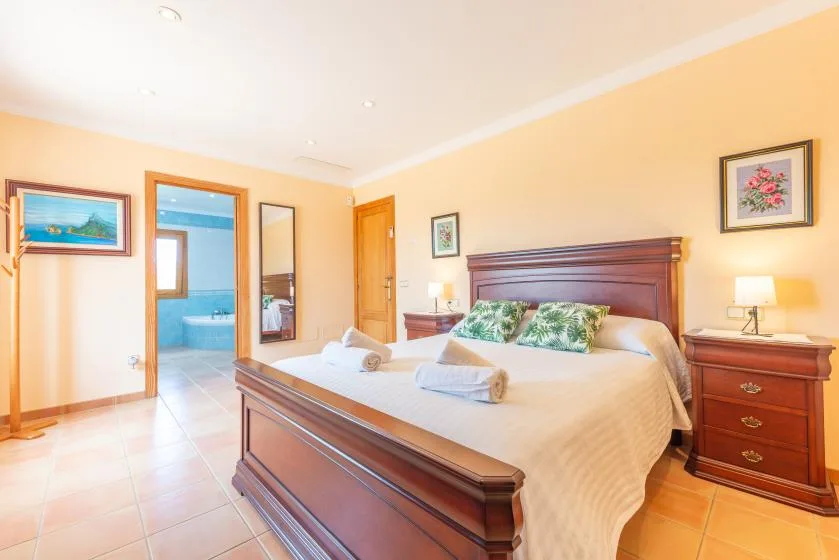 A bedroom with a large bed, wooden headboard, and matching bedside furniture.