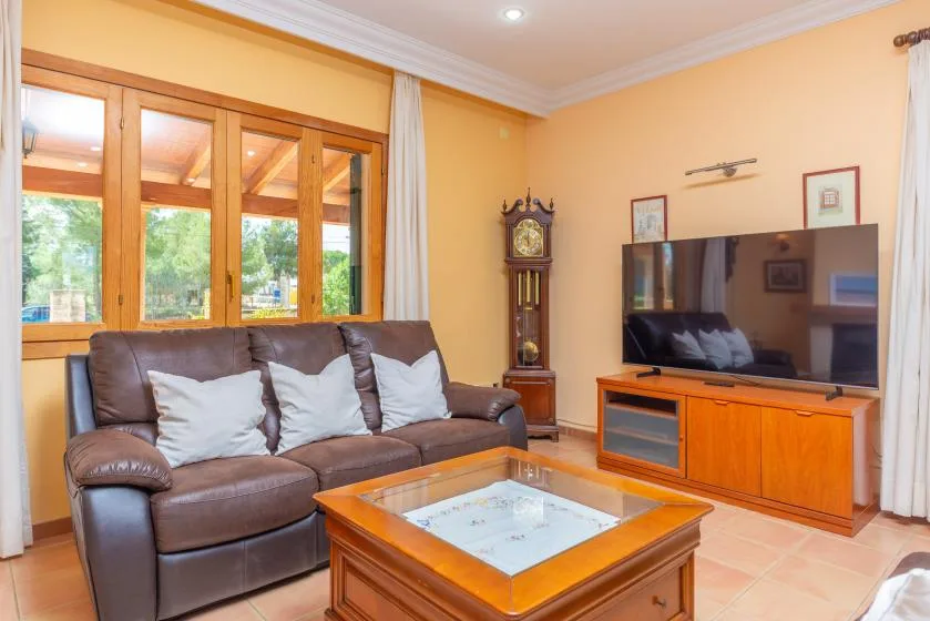 A living room with a brown seating area, television, and wooden coffee table.