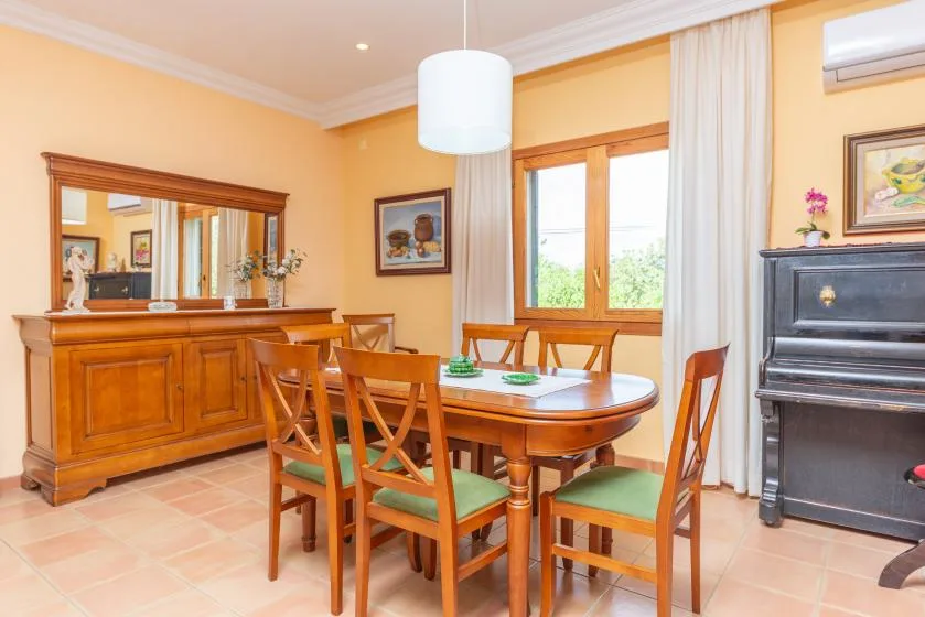 A dining room with a wooden table and chairs beside a window.