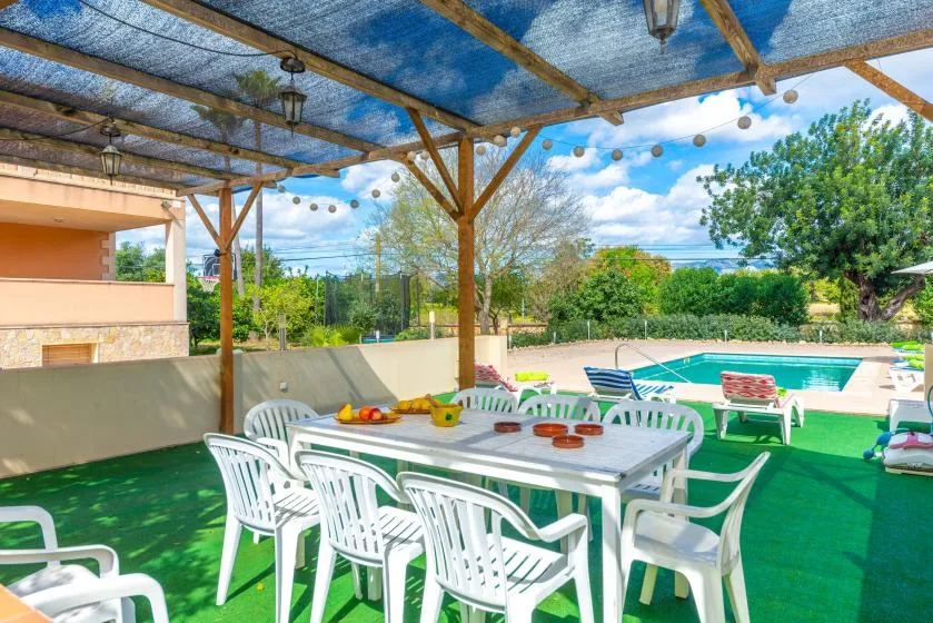 A covered outdoor dining area overlooks a swimming pool, with tables and chairs.