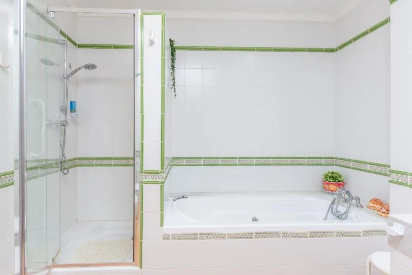 A tiled bathroom with a bathtub and glass shower.