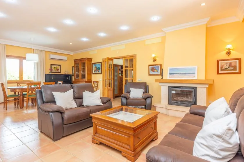 A living room with seating arranged around a wooden coffee table and fireplace.