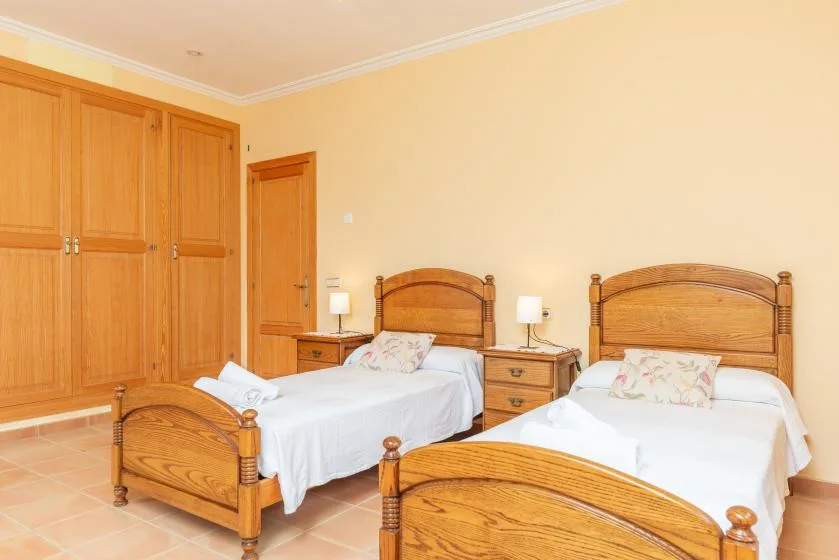 A bedroom with two beds, wooden headboards, and matching bedside tables.