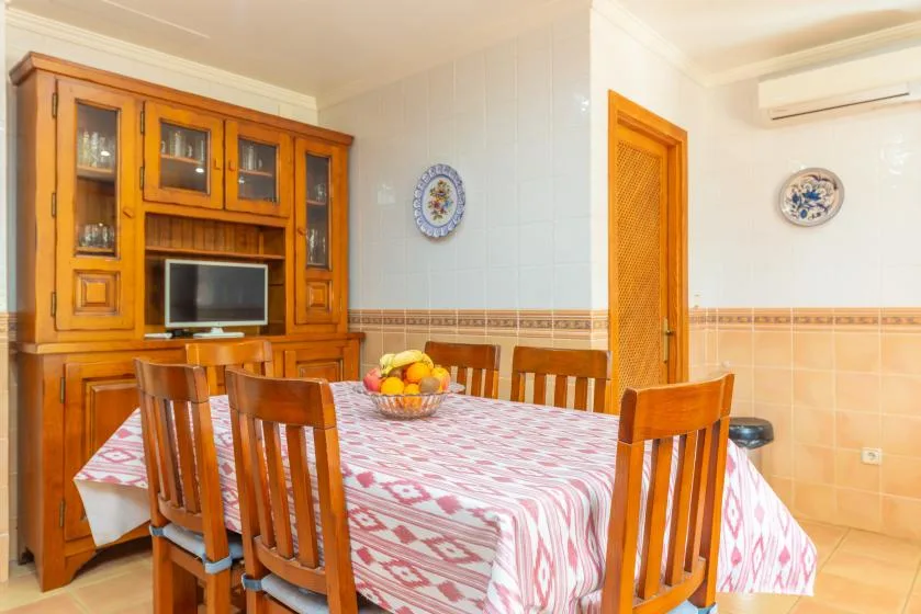 A dining room with a patterned tablecloth and wooden seating.