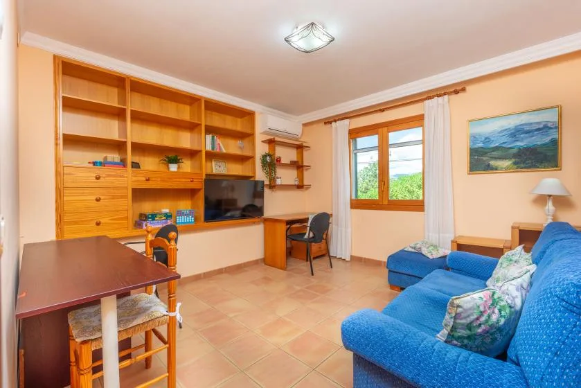 A living room with blue seating, wooden shelving, and a window.