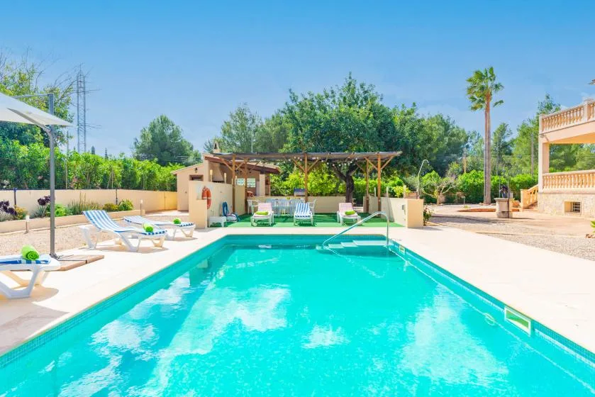 An outdoor swimming pool with lounge seating and a shaded pergola.