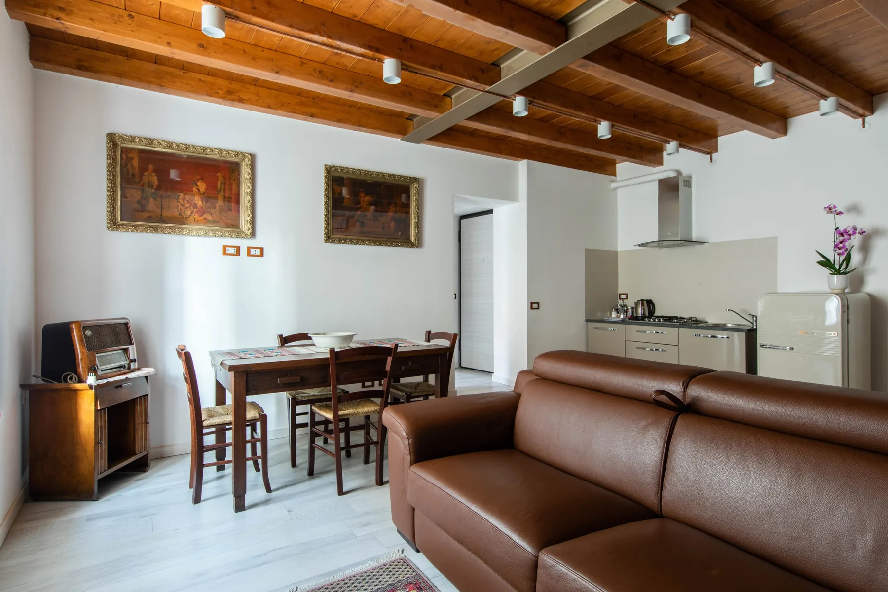 Una sala de estar y comedor con una cocina compacta y vigas de madera a la vista.