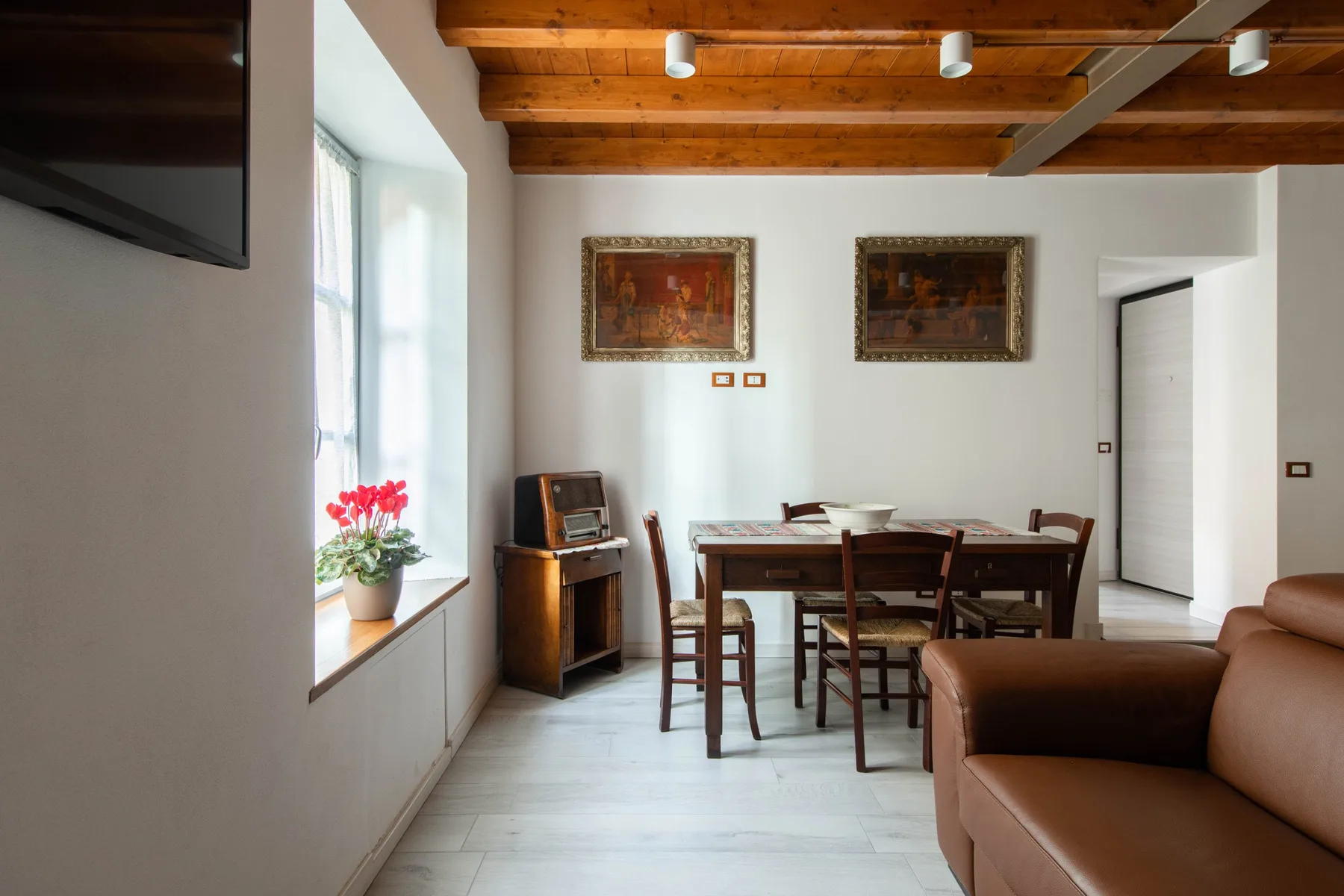 Un comedor con una mesa y sillas de madera junto a una zona de estar.