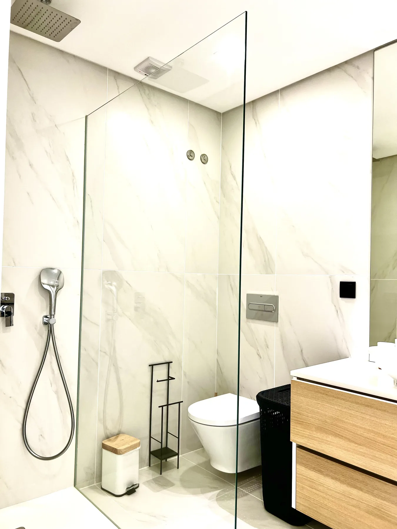 Un baño luminoso con una mampara de ducha de vidrio y un lavabo.