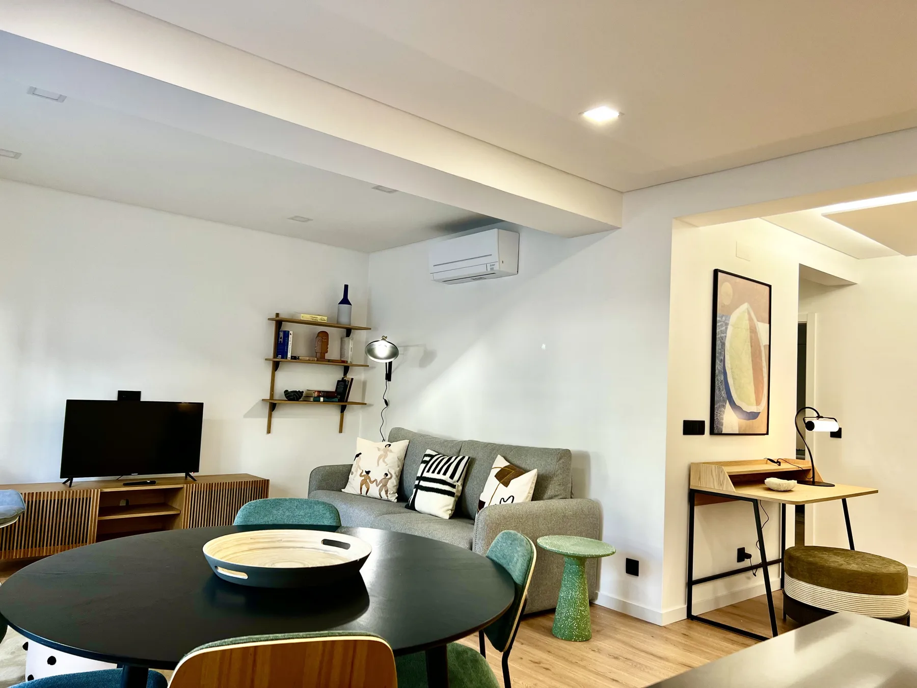 Una luminosa sala de estar y comedor tiene una mesa redonda, asientos y un televisor.