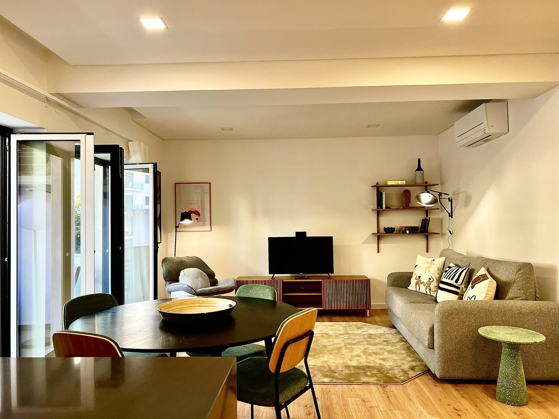 Sala de estar con zona de asientos, mesa de comedor y televisor.