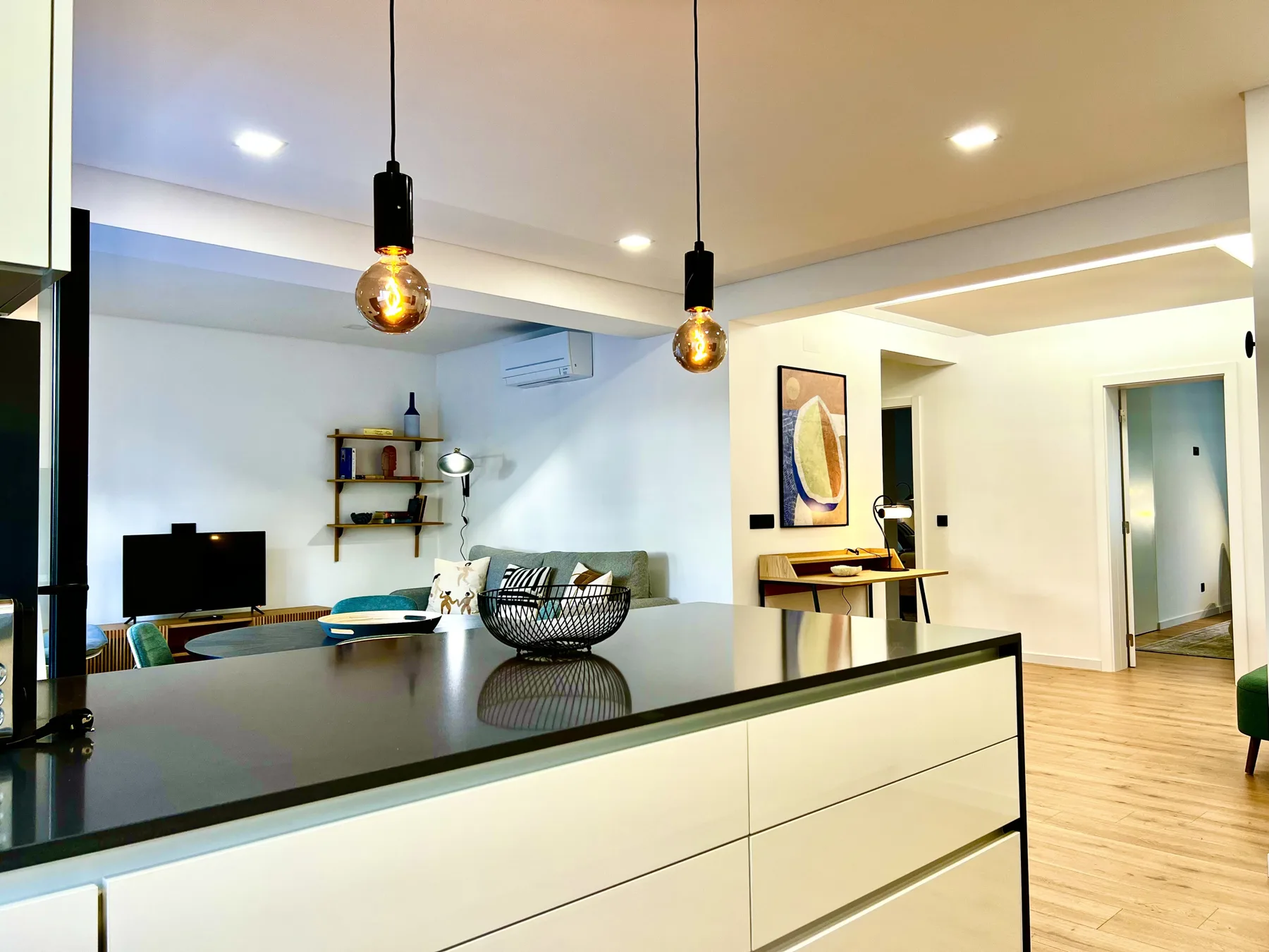 Cocina y sala de estar de concepto abierto con barra, asientos y lámparas colgantes.
