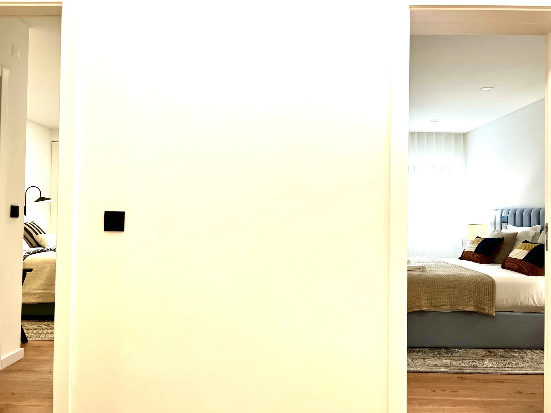 Se ve un dormitorio a través de una puerta abierta, con una cama y suelo de madera.