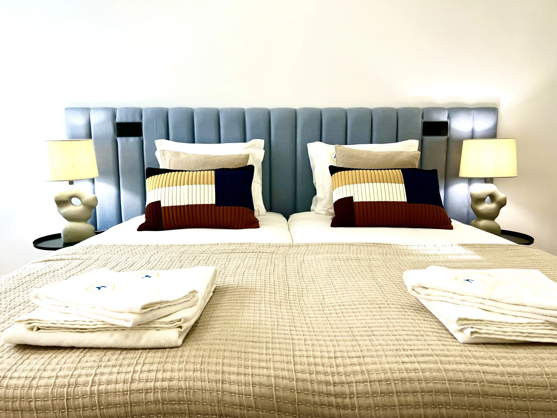 Un dormitorio con una cama grande, almohadas superpuestas y lámparas a ambos lados.