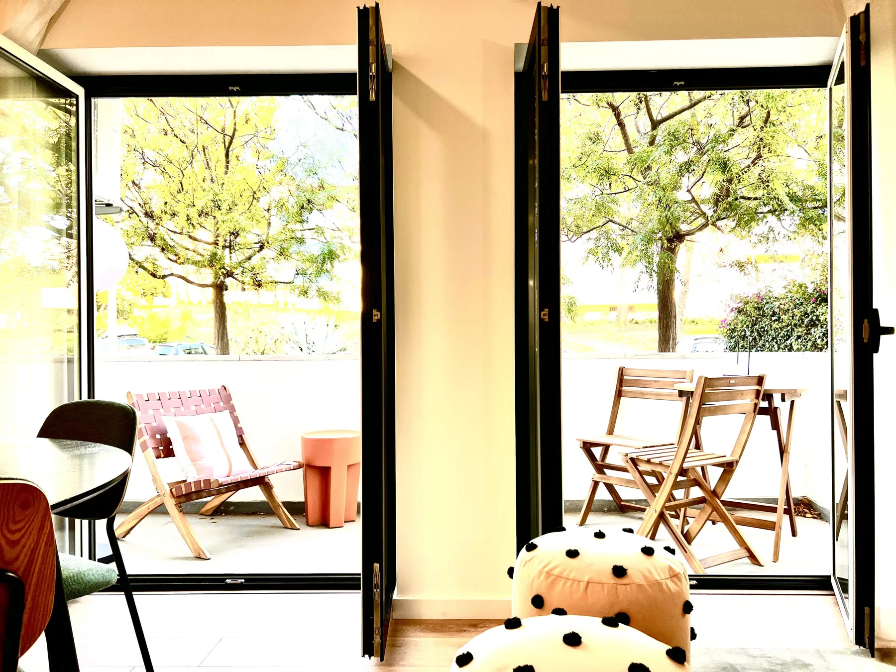 Un comedor abierto da a un patio con asientos de madera y árboles frondosos.