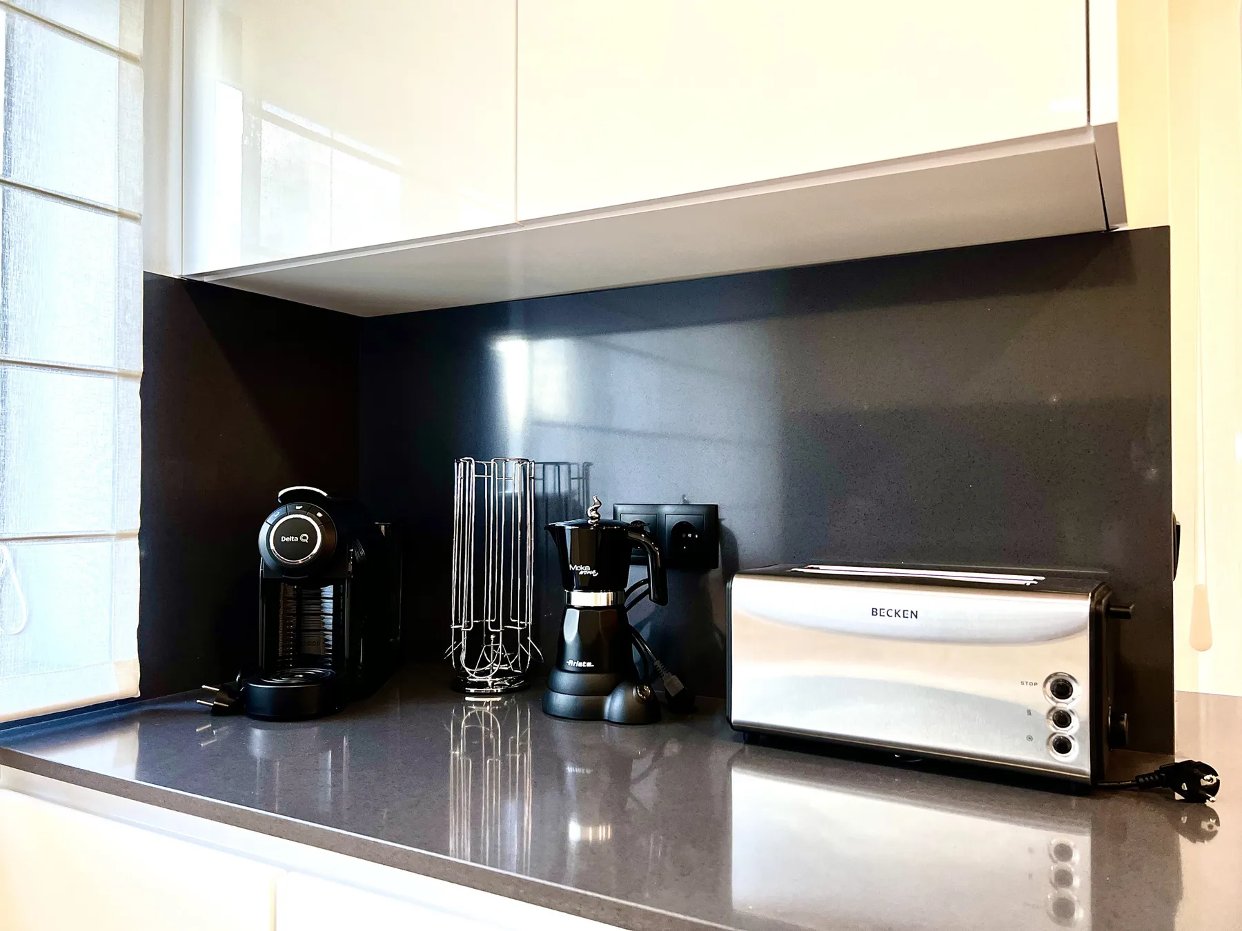 Una encimera de cocina tiene una cafetera, accesorios para café y una tostadora.
