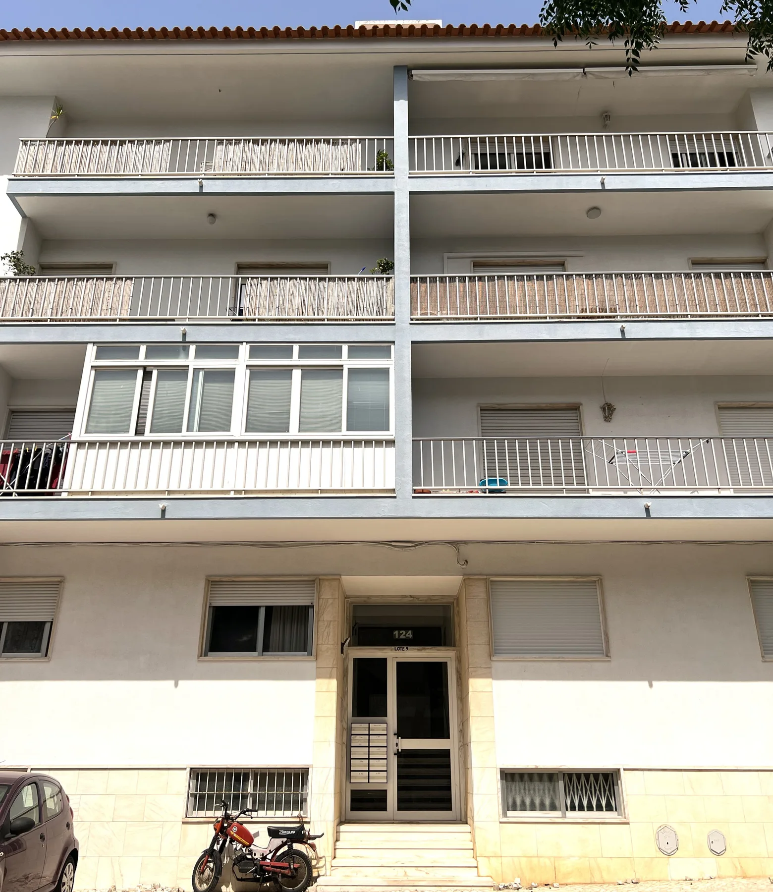 Un edificio de apartamentos de varias plantas con balcones y una entrada central.